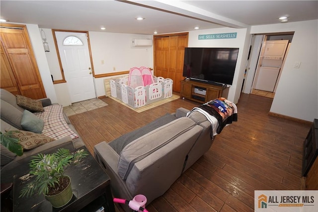 living room featuring baseboards, recessed lighting, wood-type flooring, and stacked washer / drying machine