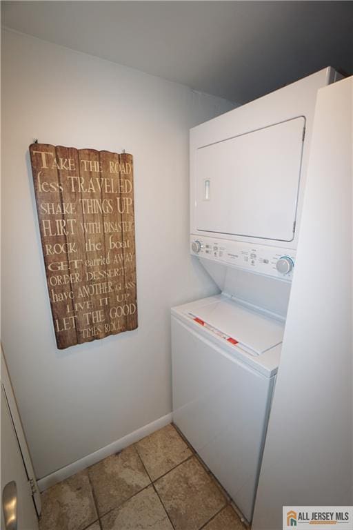 clothes washing area with laundry area, light tile patterned floors, baseboards, and stacked washer / dryer