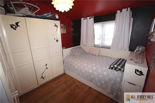 bedroom with lofted ceiling, dark wood finished floors, and a notable chandelier