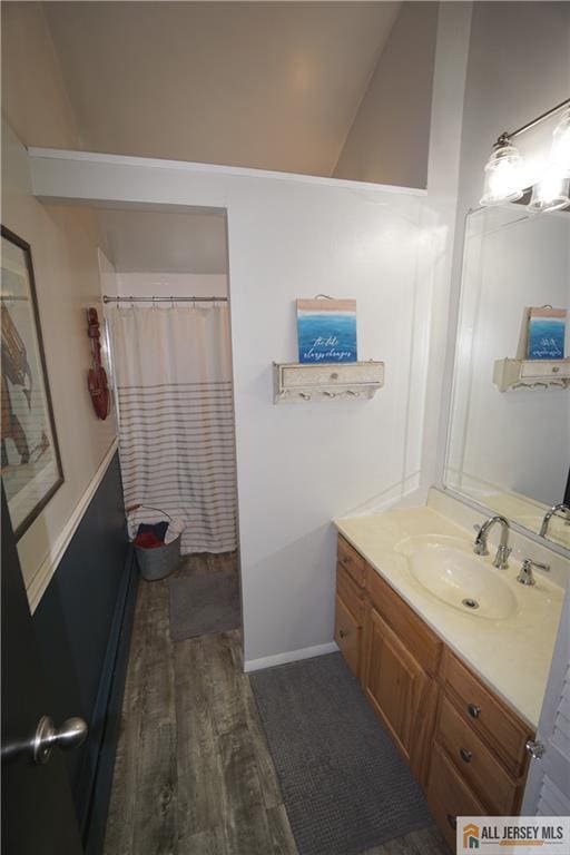 full bath with vaulted ceiling, vanity, wood finished floors, a shower with curtain, and baseboards