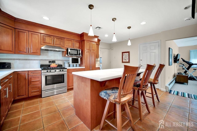 kitchen with appliances with stainless steel finishes, light countertops, brown cabinetry, backsplash, and under cabinet range hood