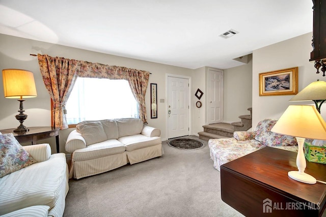 carpeted living area featuring stairs and visible vents
