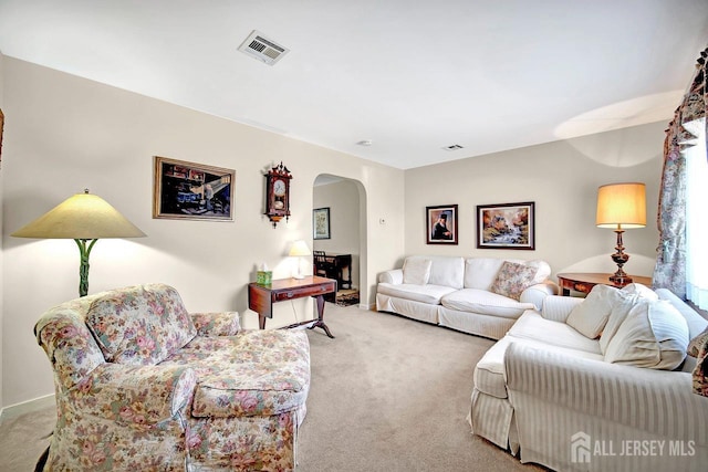 carpeted living area with arched walkways and visible vents