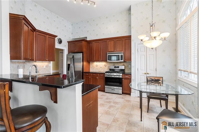 34 Schindler Ct Unit 17, Lawrence, NJ 08648 - kitchen with stainless steel appliances, wallpapered walls, dark countertops, a peninsula, and a chandelier