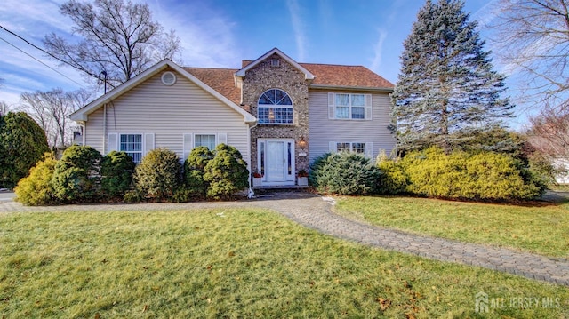 traditional home featuring a front yard, brick siding, a chimney, and roof with shingles