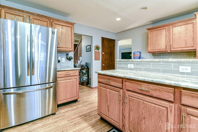 kitchen featuring light wood finished floors, light stone countertops, decorative backsplash, recessed lighting, and freestanding refrigerator