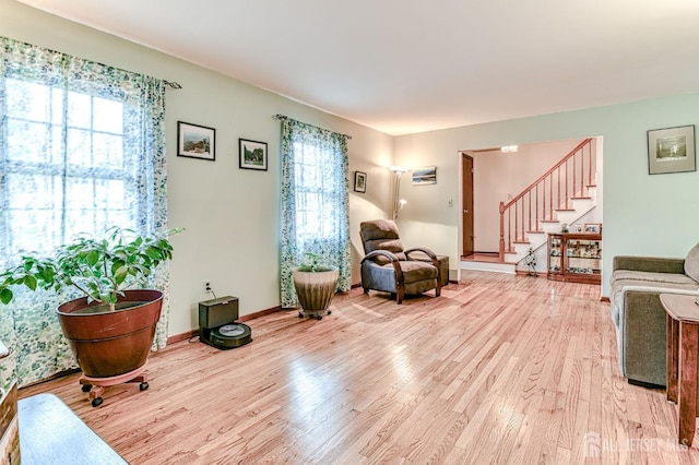 sitting room featuring light wood-type flooring, baseboards, and stairs