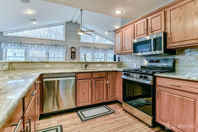 kitchen with backsplash, vaulted ceiling with beams, light stone counters, stainless steel appliances, and a sink