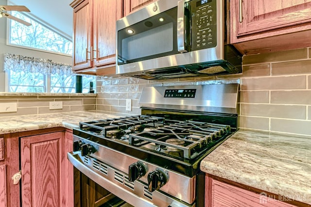 kitchen featuring ceiling fan, light stone countertops, decorative backsplash, brown cabinetry, and stainless steel appliances