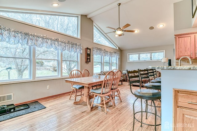 dining space featuring a ceiling fan, visible vents, high vaulted ceiling, light wood-style flooring, and beamed ceiling