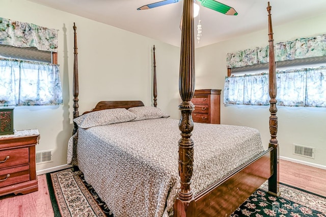 bedroom featuring visible vents, baseboards, a ceiling fan, and wood finished floors