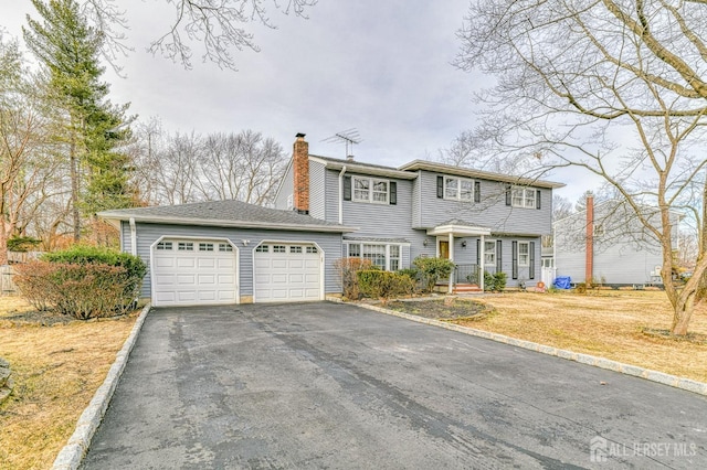 colonial home with aphalt driveway, a front lawn, a chimney, and an attached garage