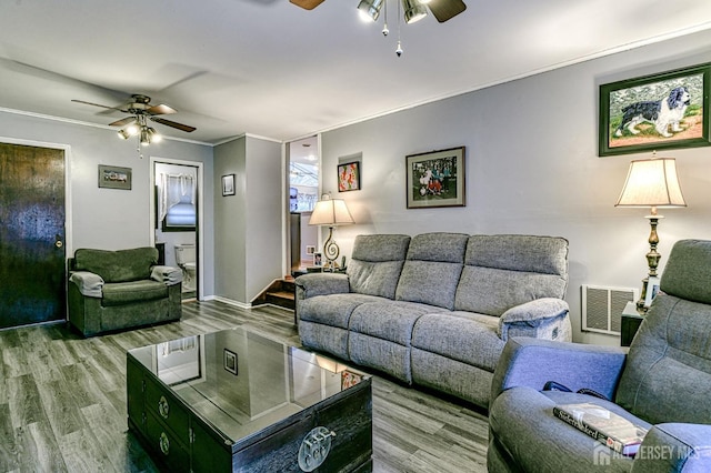 living area with visible vents, crown molding, a ceiling fan, and wood finished floors