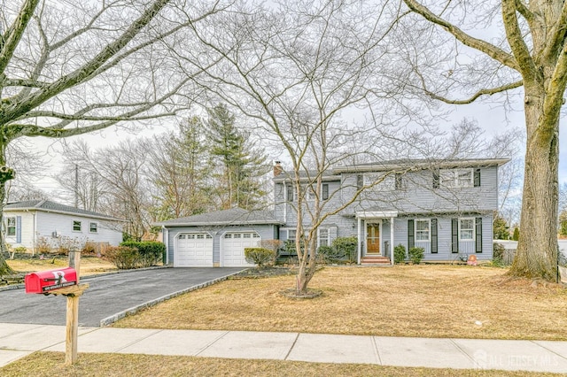 colonial inspired home with an attached garage, driveway, and a chimney