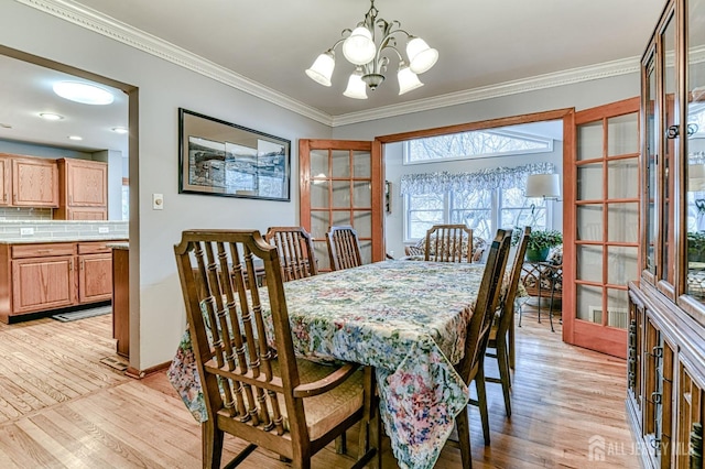 dining room with an inviting chandelier, crown molding, baseboards, and light wood-type flooring