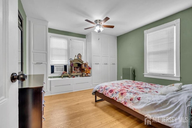 bedroom featuring ceiling fan, cooling unit, radiator, and light wood-style flooring