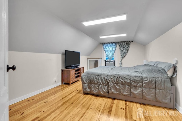 bedroom featuring baseboards, hardwood / wood-style floors, and vaulted ceiling