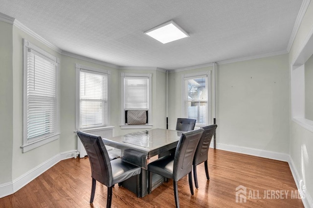 dining area with crown molding, baseboards, and wood finished floors