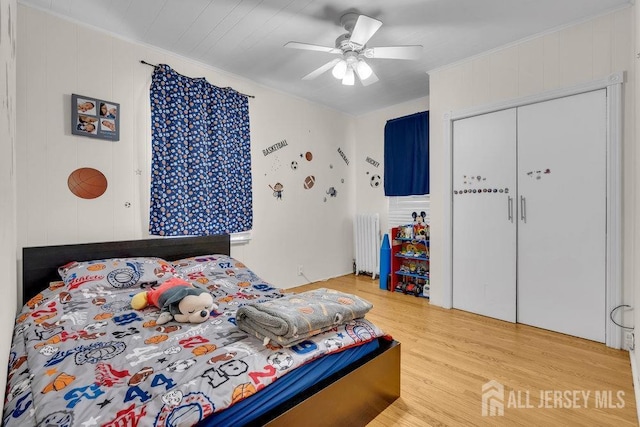 bedroom featuring a closet, light wood-style flooring, radiator, and a ceiling fan