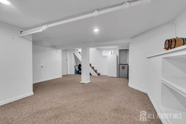 basement with stairway, freestanding refrigerator, baseboards, and carpet floors