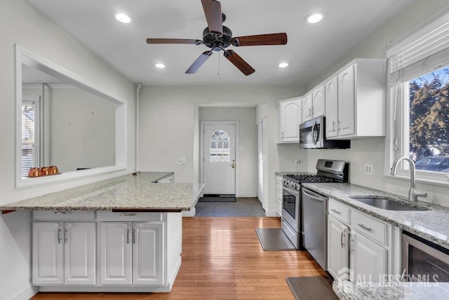 kitchen featuring white cabinets, beverage cooler, appliances with stainless steel finishes, and a sink