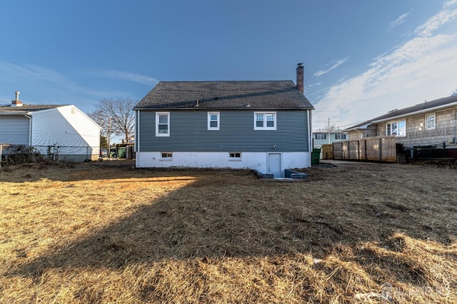 rear view of house with a yard, a chimney, and fence