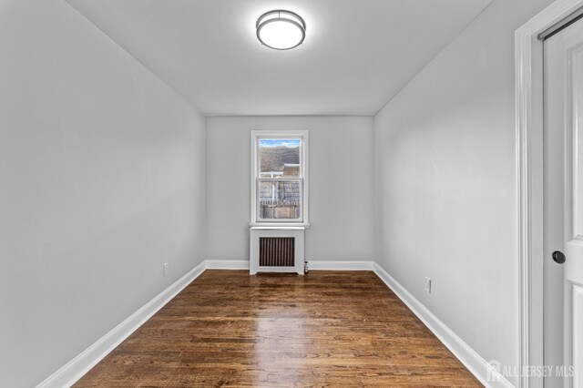 spare room featuring radiator heating unit and dark hardwood / wood-style flooring