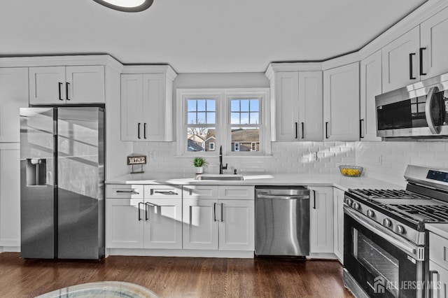 kitchen with dark wood-style floors, stainless steel appliances, light countertops, and a sink