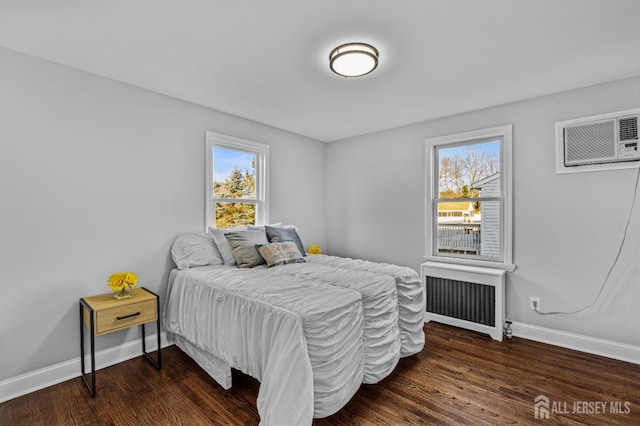 bedroom with a wall mounted AC, dark hardwood / wood-style floors, radiator, and multiple windows