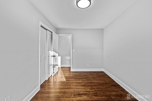 interior space featuring a closet, baseboards, and dark wood finished floors