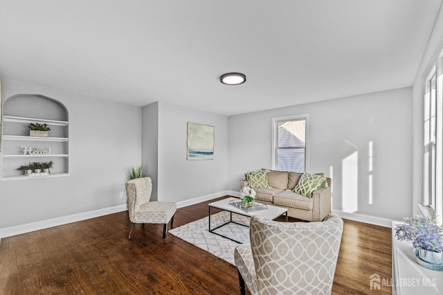 living room featuring built in features, wood finished floors, and baseboards