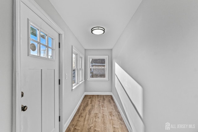 doorway featuring light wood finished floors and baseboards