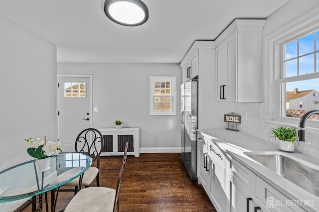 kitchen featuring dark wood-type flooring, decorative backsplash, stainless steel refrigerator with ice dispenser, white cabinetry, and a sink