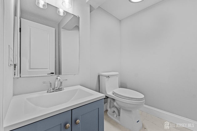 bathroom with vanity, toilet, baseboards, and marble finish floor