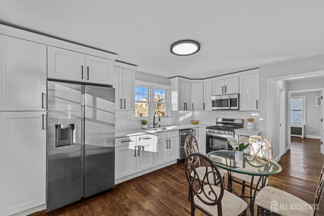 kitchen featuring sink, backsplash, white cabinets, and appliances with stainless steel finishes