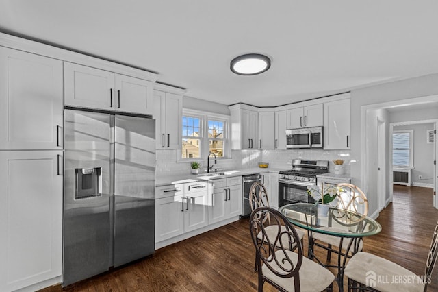 kitchen with backsplash, appliances with stainless steel finishes, light countertops, and a sink