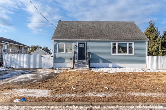 view of front of house featuring entry steps, a gate, fence, and roof with shingles