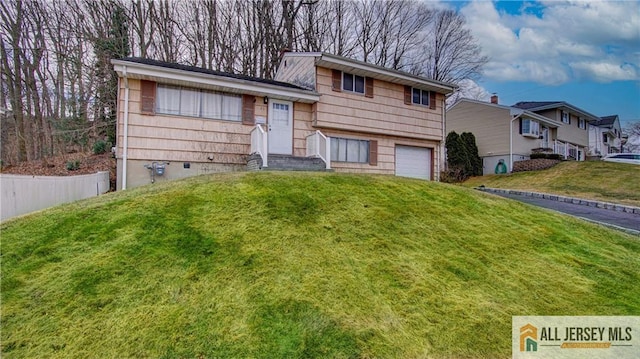 split level home featuring an attached garage, driveway, a residential view, and a front yard