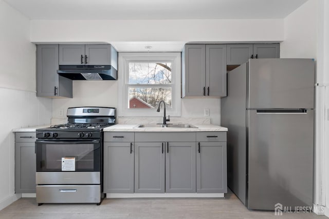 kitchen with under cabinet range hood, appliances with stainless steel finishes, and gray cabinets