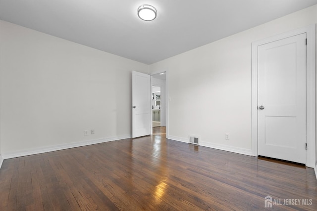 empty room featuring baseboards, visible vents, and dark wood-type flooring