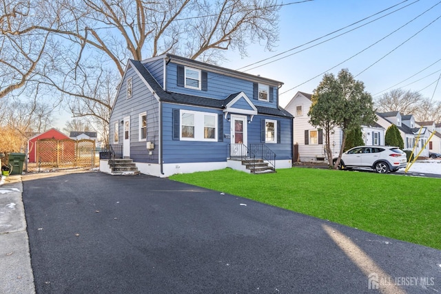 view of front of home with roof with shingles and a front yard