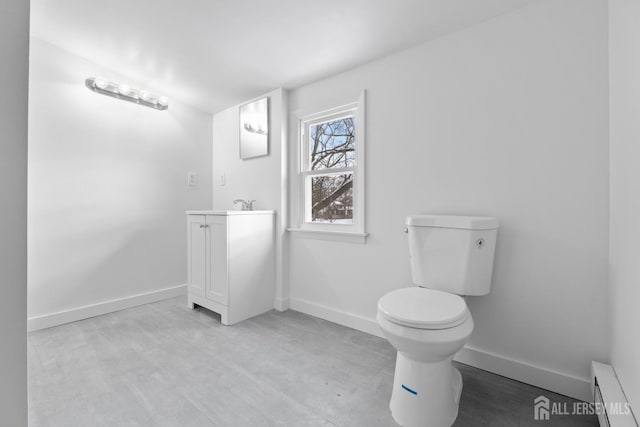 half bath with baseboard heating, toilet, vanity, and baseboards