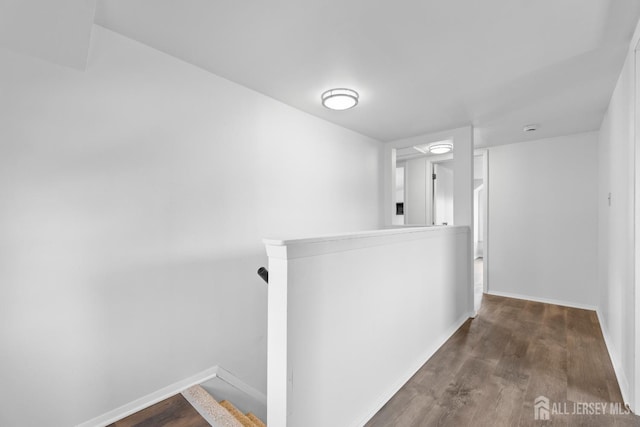 hallway with baseboards, an upstairs landing, and wood finished floors