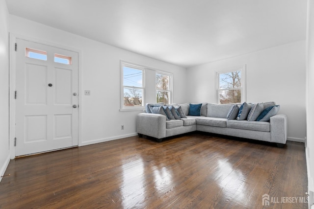 unfurnished living room with baseboards and dark wood-type flooring