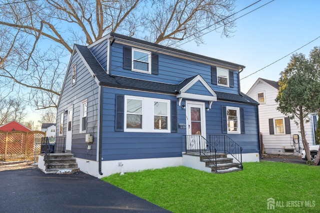 view of front facade with roof with shingles and a front yard