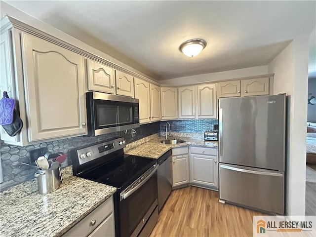 133 Pleasant Ave, Iselin, NJ 08830 - kitchen featuring stainless steel appliances, a sink, light wood finished floors, backsplash, and light stone countertops