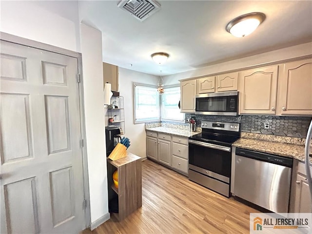 133 Pleasant Ave, Iselin, NJ 08830 - kitchen with stainless steel appliances, light wood finished floors, decorative backsplash, light stone counters, and baseboards