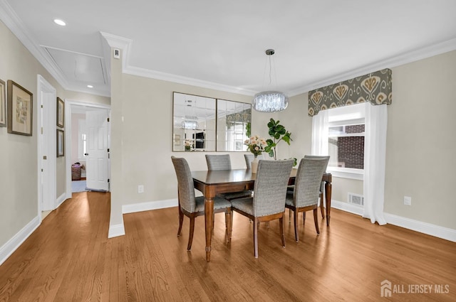 dining space featuring attic access, crown molding, baseboards, and wood finished floors