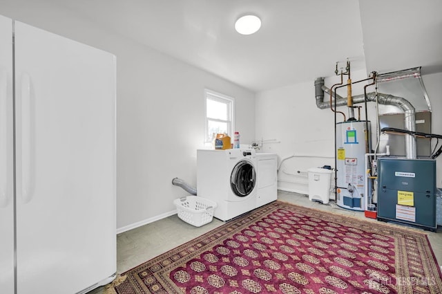 clothes washing area featuring laundry area, water heater, washer and clothes dryer, and baseboards