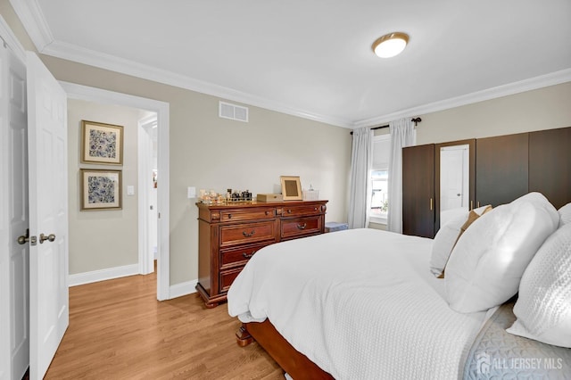 bedroom featuring ornamental molding, light wood-type flooring, visible vents, and baseboards